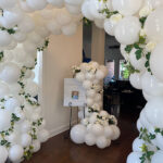 White balloon arch and column with flowers